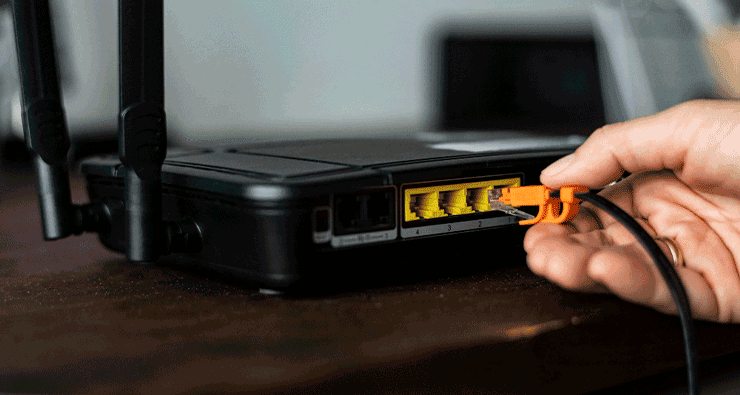 Uma pessoa está conectando um cabo de rede a um roteador