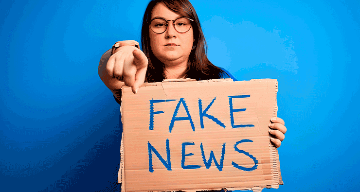 Uma mulher segurando uma placa de papelão que diz fake news