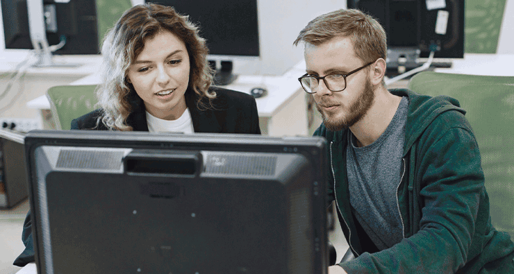Um homem e uma mulher olhando para a tela de um computador