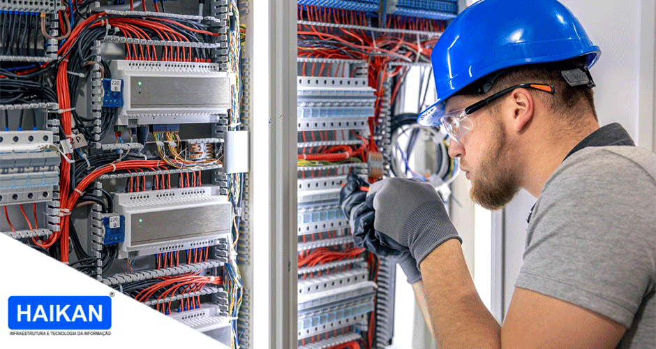 Técnico com capacete azul instalando sistema de cabeamento estruturado em painel elétrico