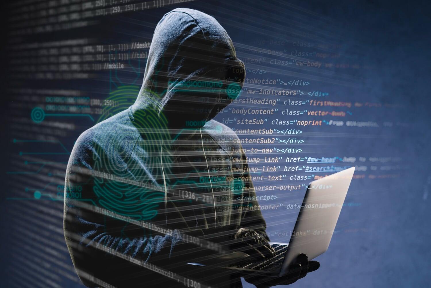 Hacker com notebook em ambiente escuro, representando risco de segurança digital