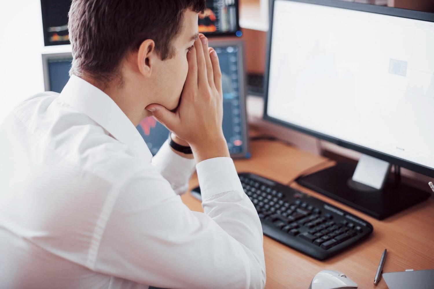 Profissional preocupado diante de falha em sistema de TI, analisando gráficos de desempenho no computador