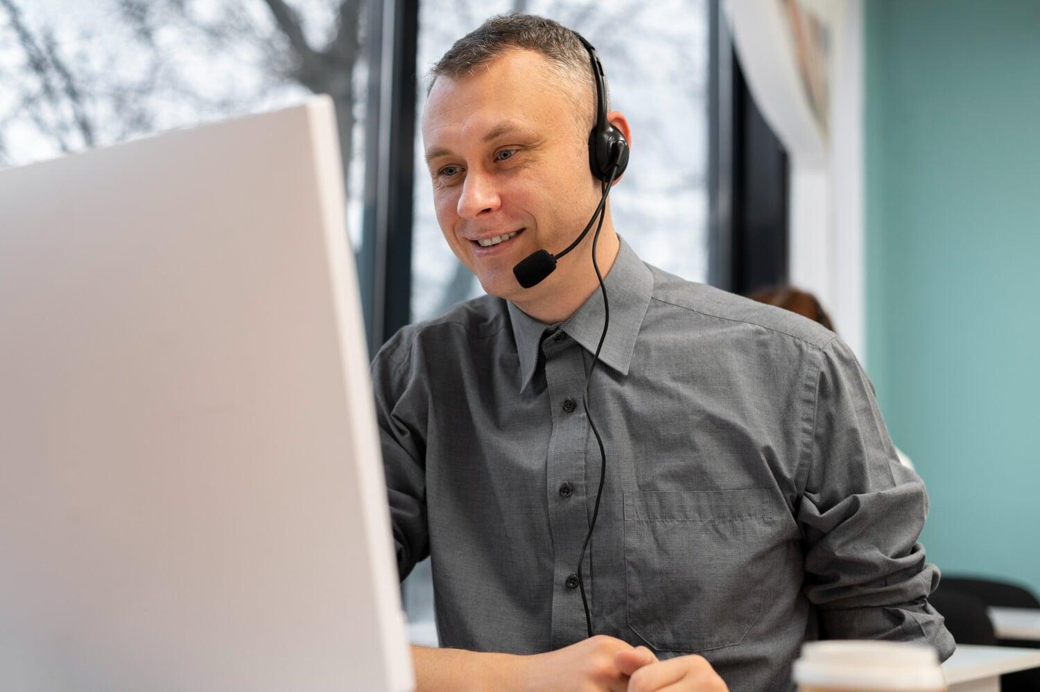 Profissional de suporte de TI sorrindo com headset durante atendimento online