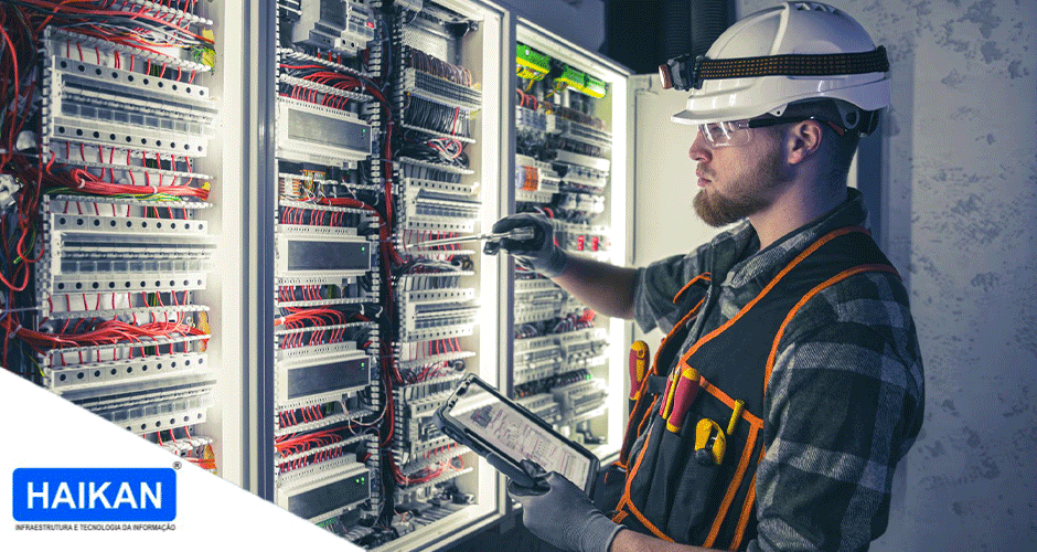 Técnico especializado realizando manutenção em painel elétrico com cabeamento estruturado